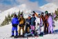 A group photo of skiers and snowboarders atop a mountain.